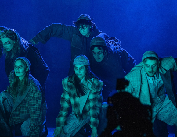 Zdjęcie przedstawia aktorów w płaszczach i czapkach na głowie patrzących groźnym wzrokiem.