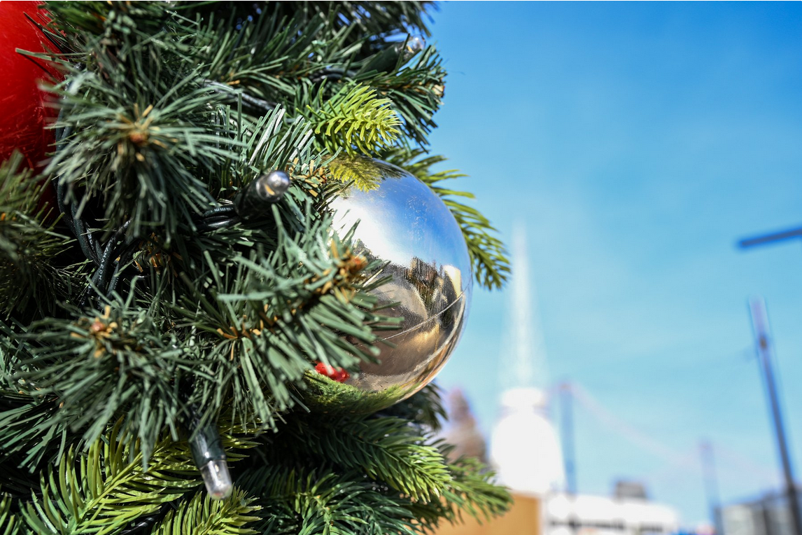 Zdjęcie przedstawia bombkę na choince. W tle widać rozmazaną iglicę na Międzynarodowych Targach Poznańskich.