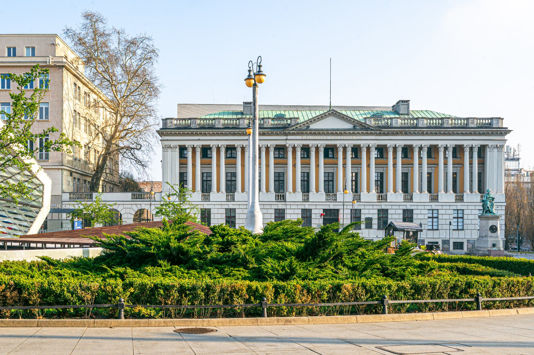 Zdjęcie przedstawia budynek biblioteki i zieleń na Placu Wolności.