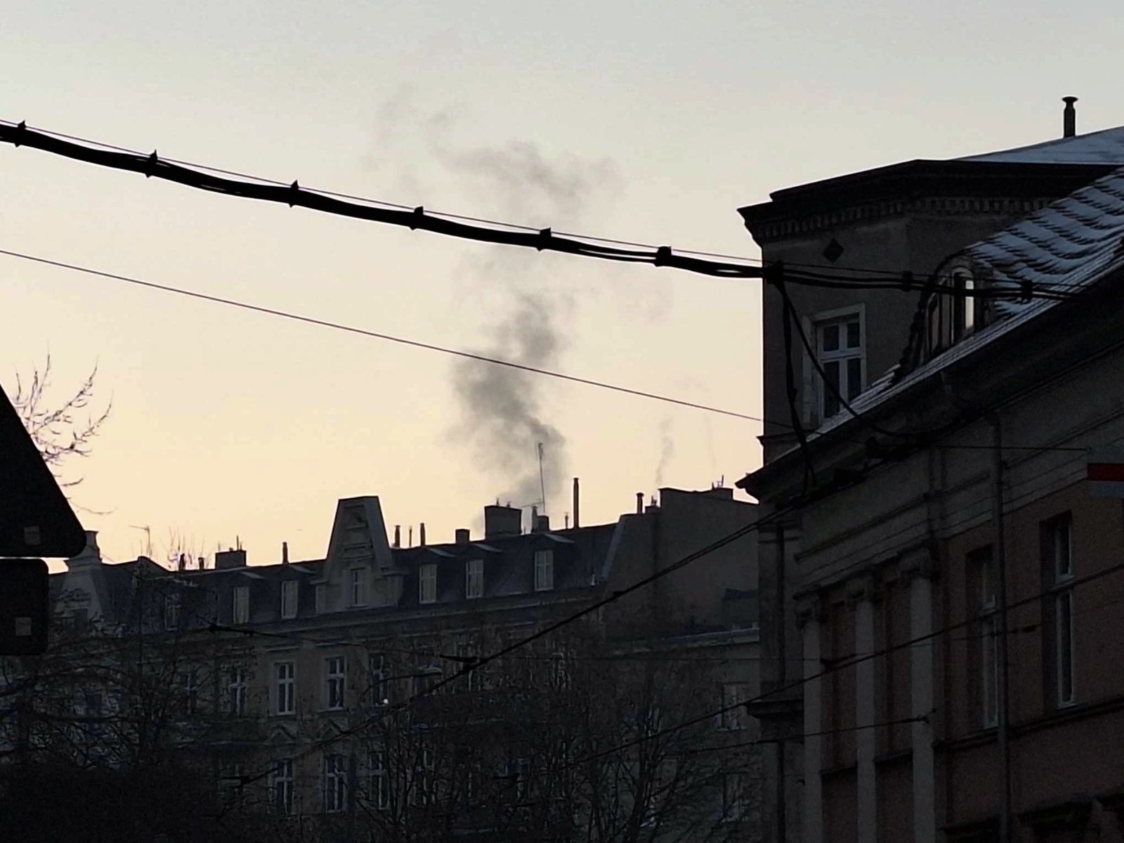 Zdjęcie przedstawia budynki i dymiący komin.