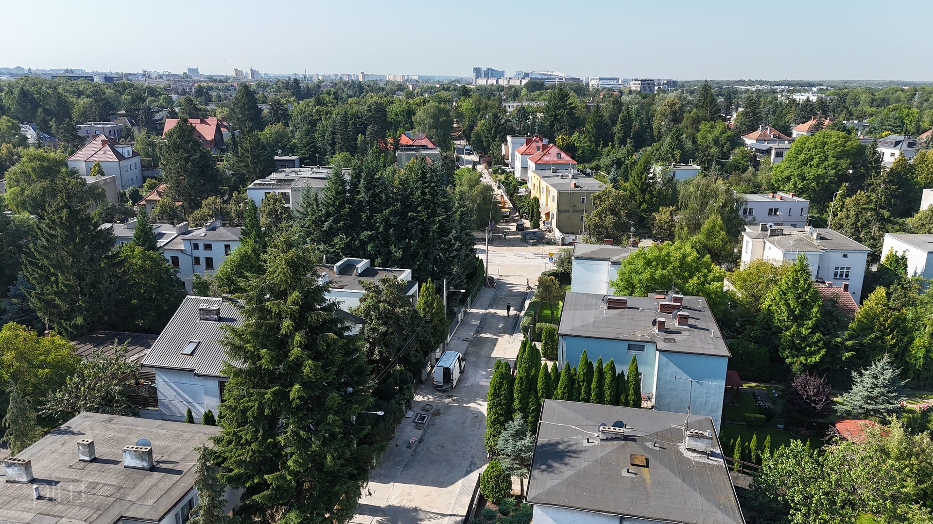 Zdjęcie przedstawia budynki, zieleń i remontowaną ulicę z lotu ptaka.