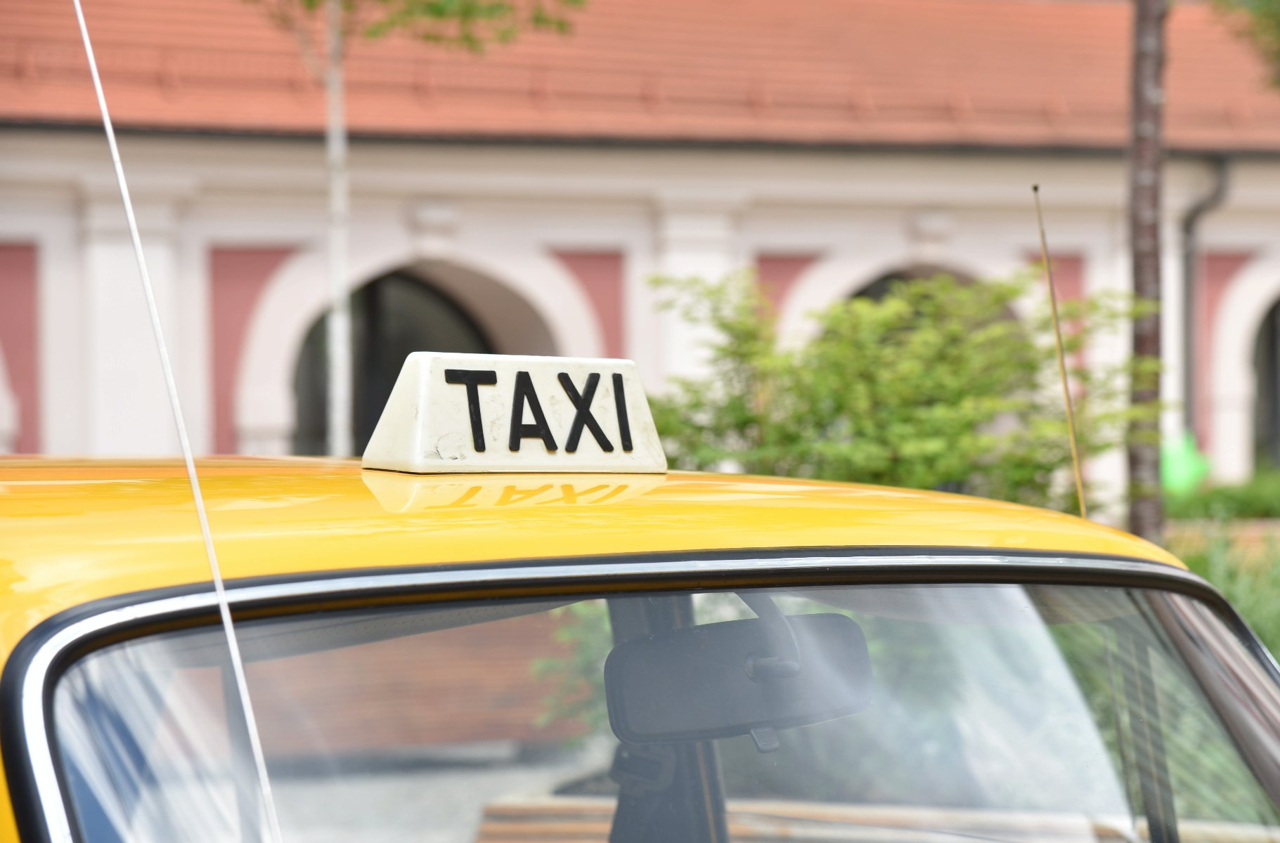 Zdjęcie przedstawia dach samochodu, na którym znajduje się tabliczka z napisem taxi.