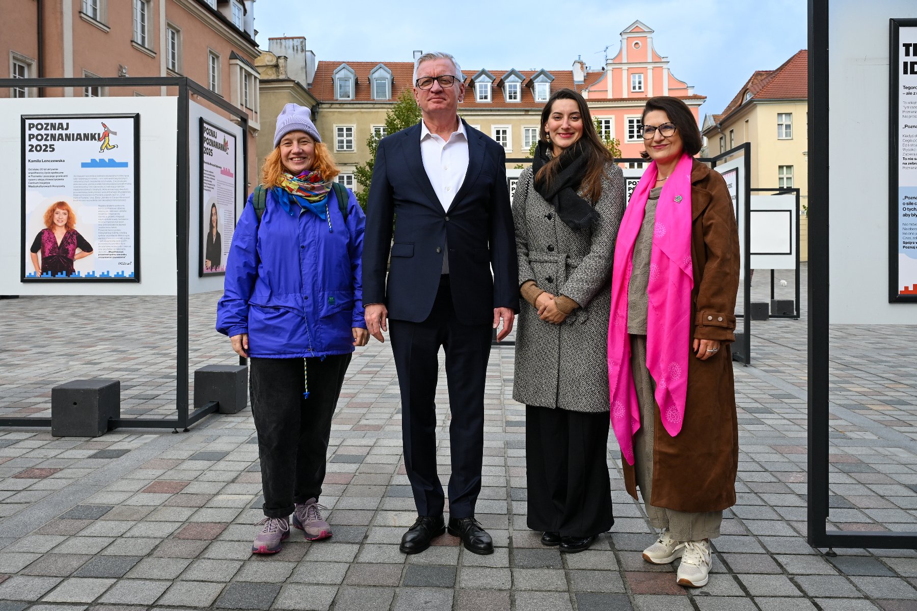 Zdjęcie przedstawia dwie kobiety i mężczyznę. Mężczyzna trzyma w ręku mikrofon. Za ich plecami znajduje sie wystawa.