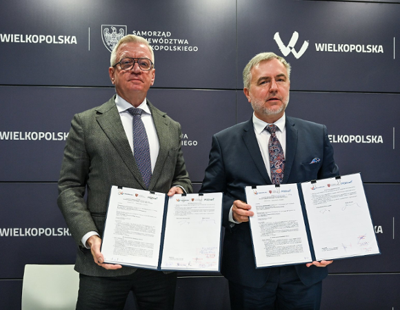 Zdjęcie przedstawia dwóch mężczyzn - prezydenta i marszałka - pozujących do zdjęcia. W rękach trzymają podpisane umowy.