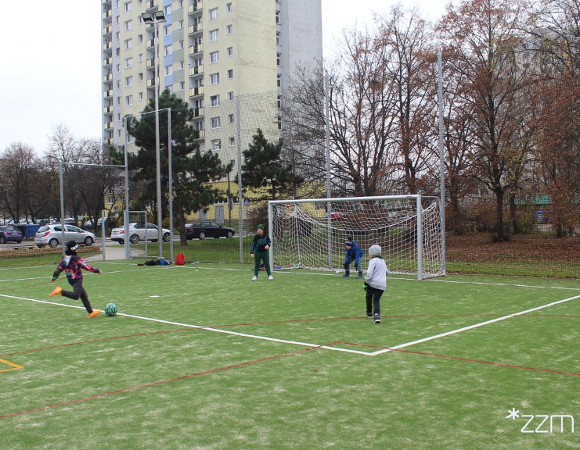 Zdjęcie przedstawia dzieci grające w piłkę na boisku.