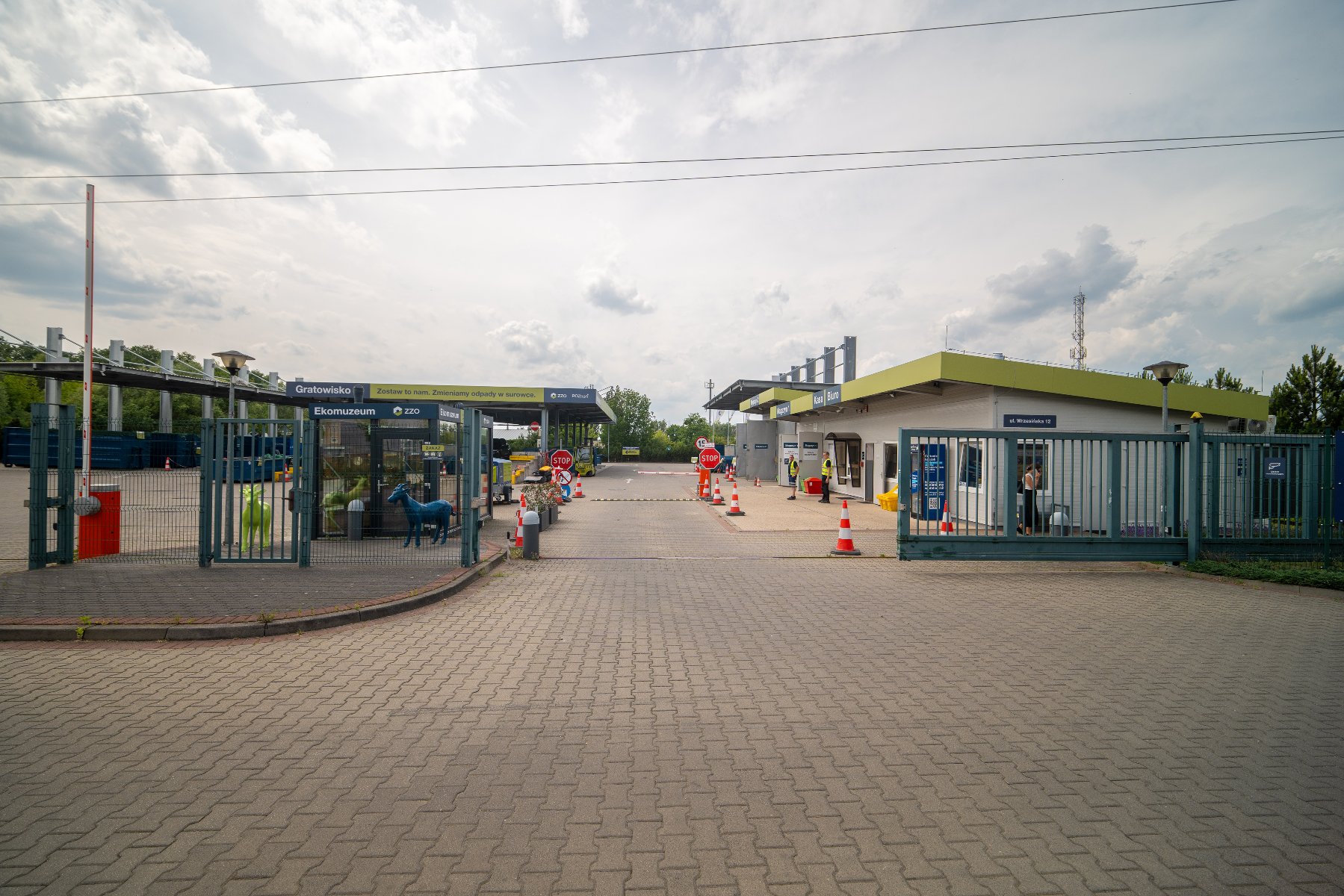 Zdjęcie przedstawia gratowisko. Widać na nim plac i kontenery, pod które można podjechać samochodem, a także szyld z napisem gratowisko i adresem strony internetowej ZZO.