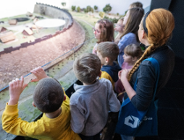 Zdjęcie przedstawia grupę dzieci stojących przy muzealnej ekspozycji obrazującej dawny gród.