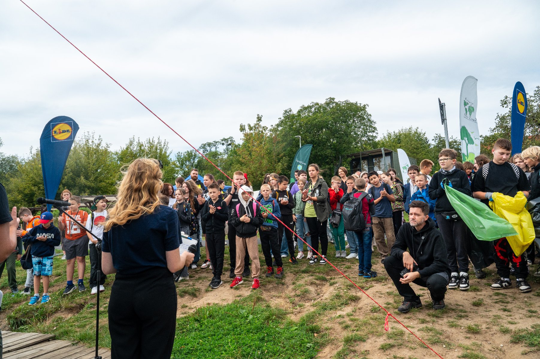 Zdjęcie przedstawia grupę dziewczyn podnoszących śmieci z trawy.