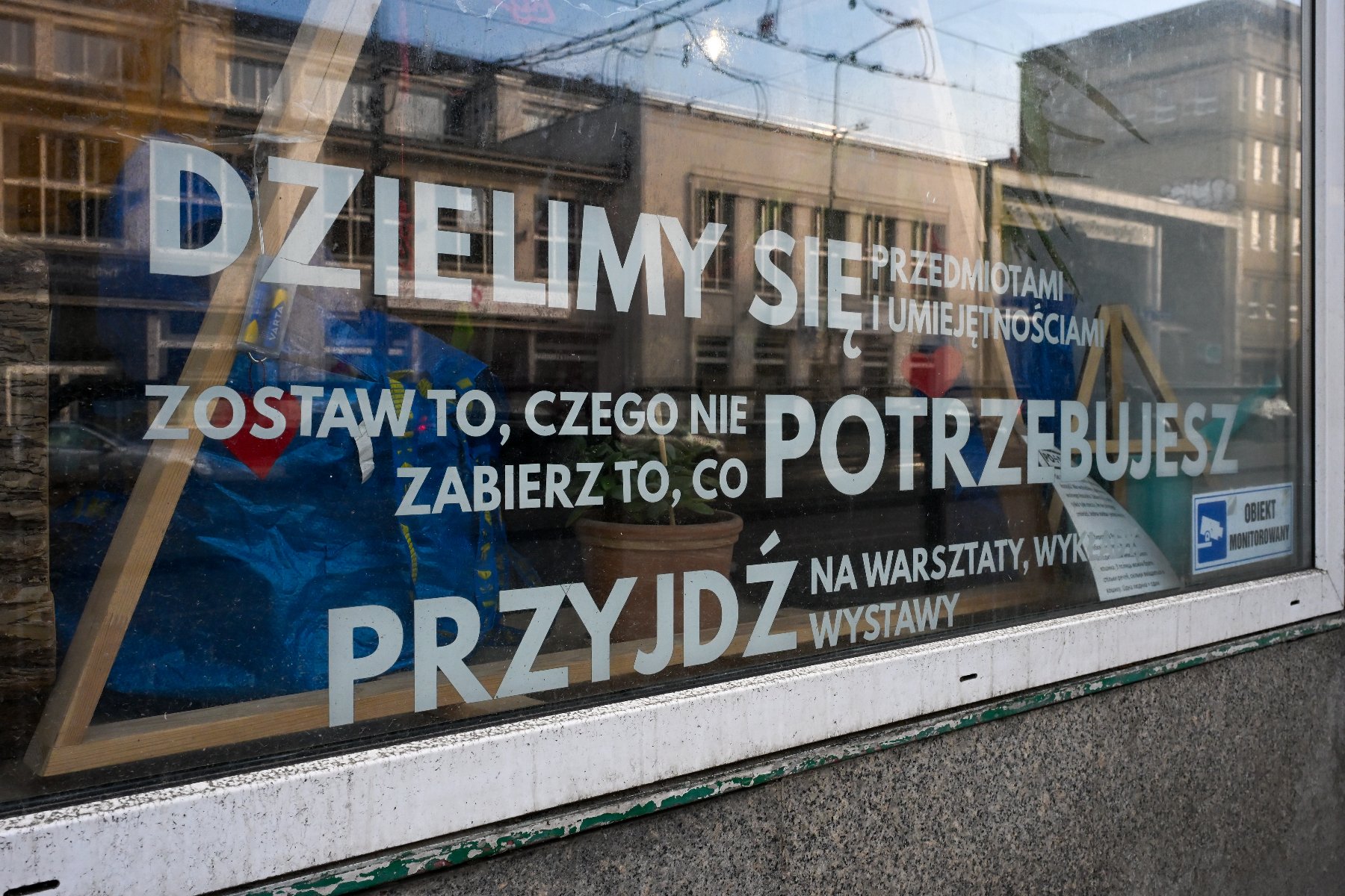 Zdjęcie przedstawia kobietę przeglądającą wieszaki z ubraniami.
