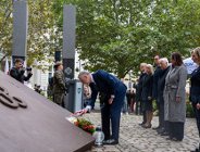 Zdjęcie przedstawia ludzi stojących przed pomnikiem.