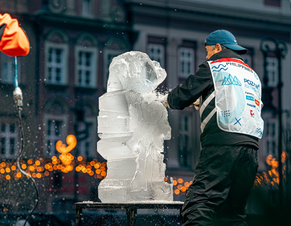 Zdjęcie przedstawia mężczyznę rzeźbiącego w lodzie.