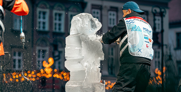 Zdjęcie przedstawia mężczyznę rzeźbiącego w lodzie.