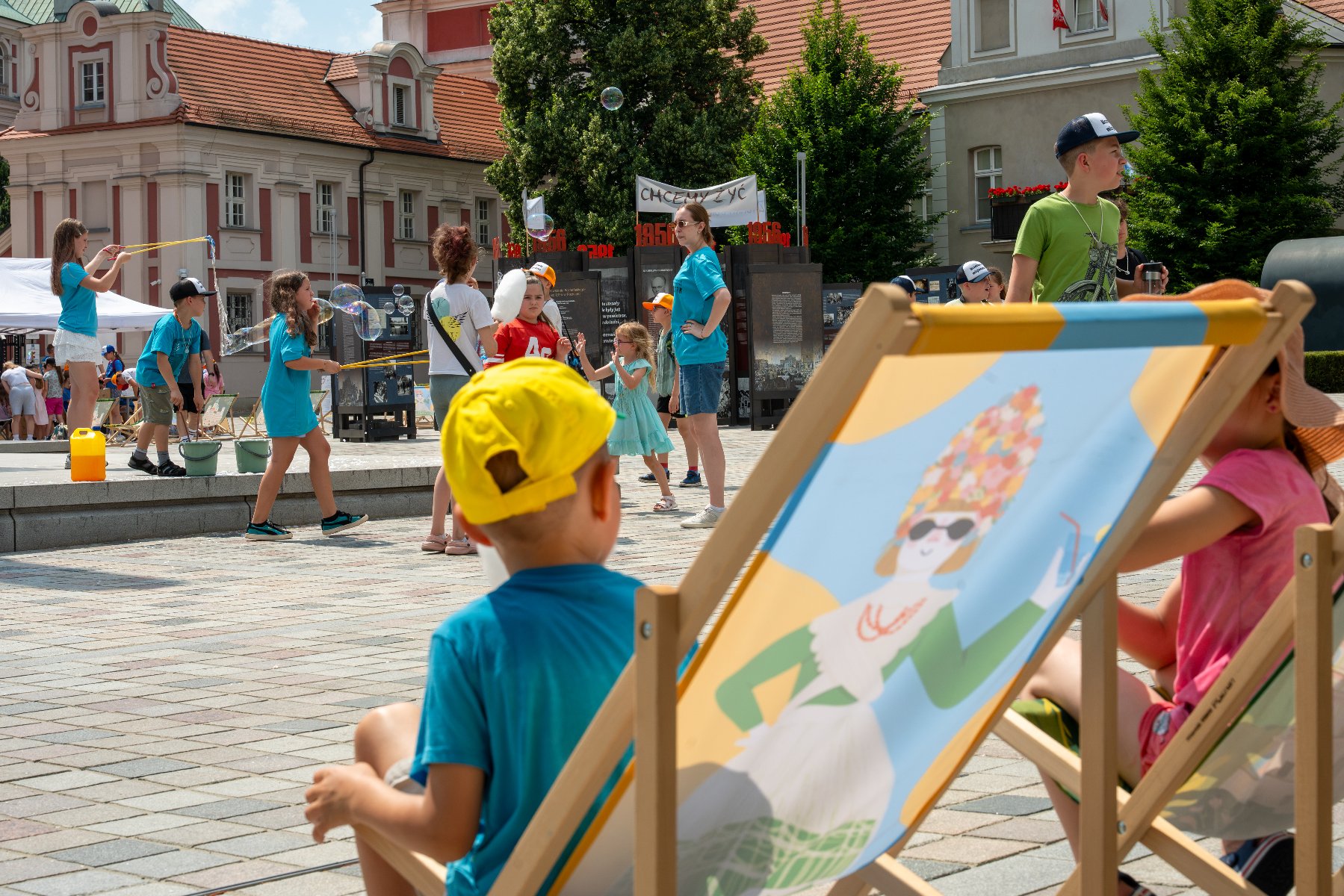 Zdjęcie przedstawia mężyczyznę w średniowiecznym przebraniu, stojącą obok niego dziewczynke i leżące na stole hełmy.