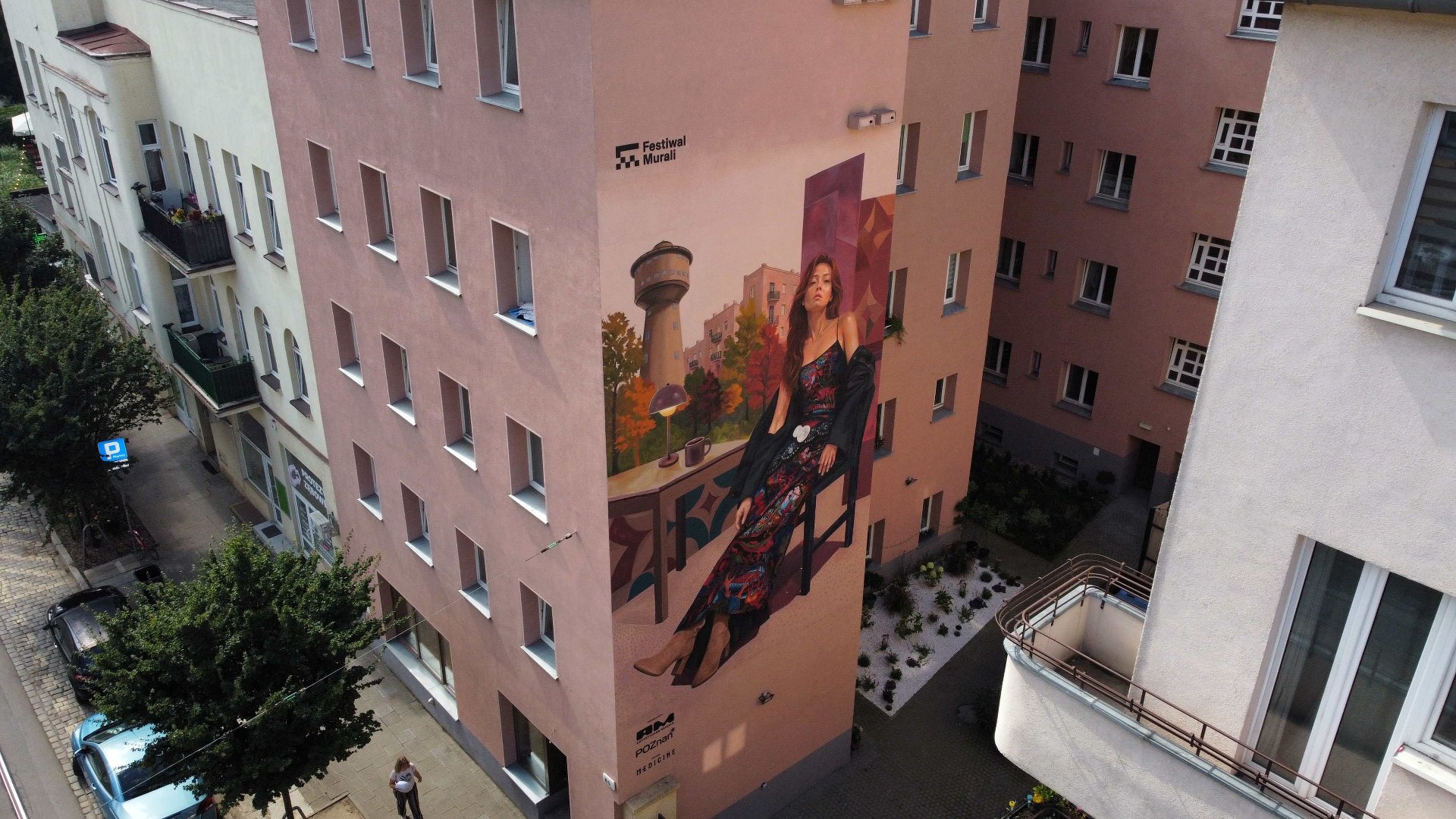 Zdjęcie przedstawia mural na ścienie budynku. Przedstawia on starszego mężczyznę z rowerem.