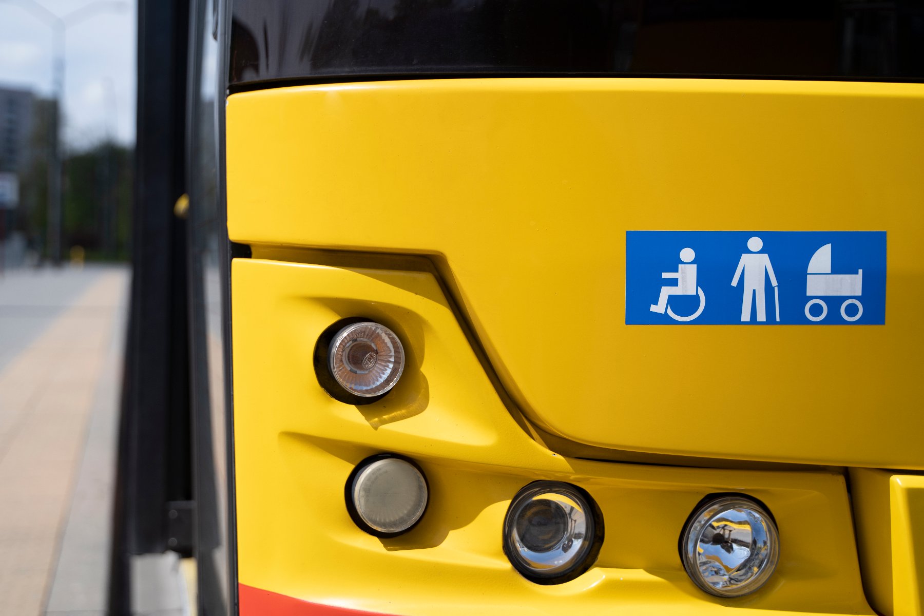 Zdjęcie przedstawia osobę na wózku inwalidzkim wjeżdząjącą do autobusu.