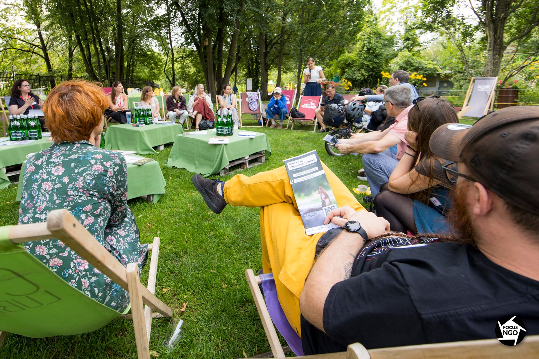 Zdjęcie przedstawia osoby siedzące na leżakach na terenie zielonym - uczestników spotkania międzysektorowego