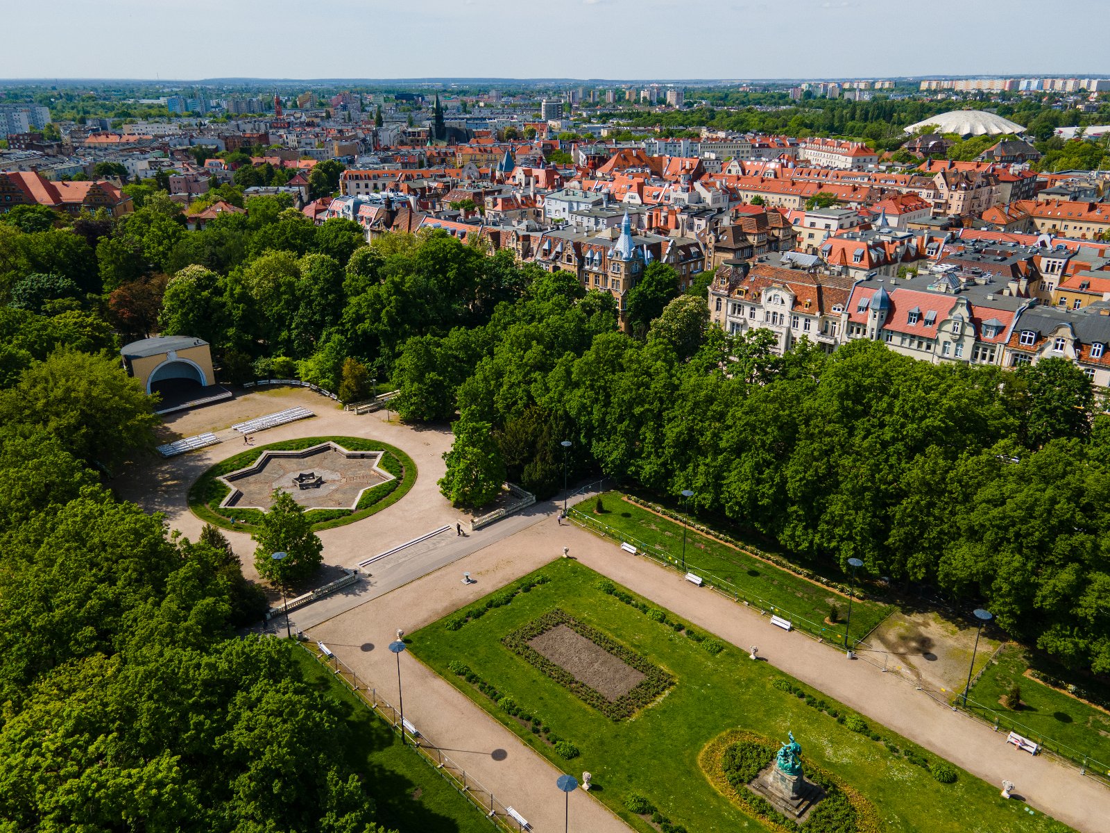 Zdjęcie przedstawia park ze sceną plenerową oraz otaczającegogo budynki z lotu ptaka.