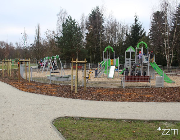 Zdjęcie przedstawia plac zabaw za ogrodzeniem.