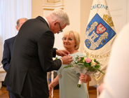 Zdjęcie przedstawia prezydenta przypinającego medal kobiecie. Obok widać flagę z herbem Poznania.