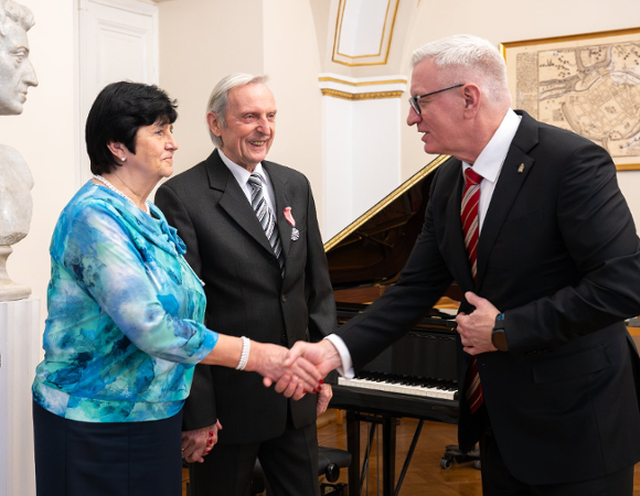 Zdjęcie przedstawia prezydenta ściskającego rękę kobiecie. Obok stoi mężczyzna.