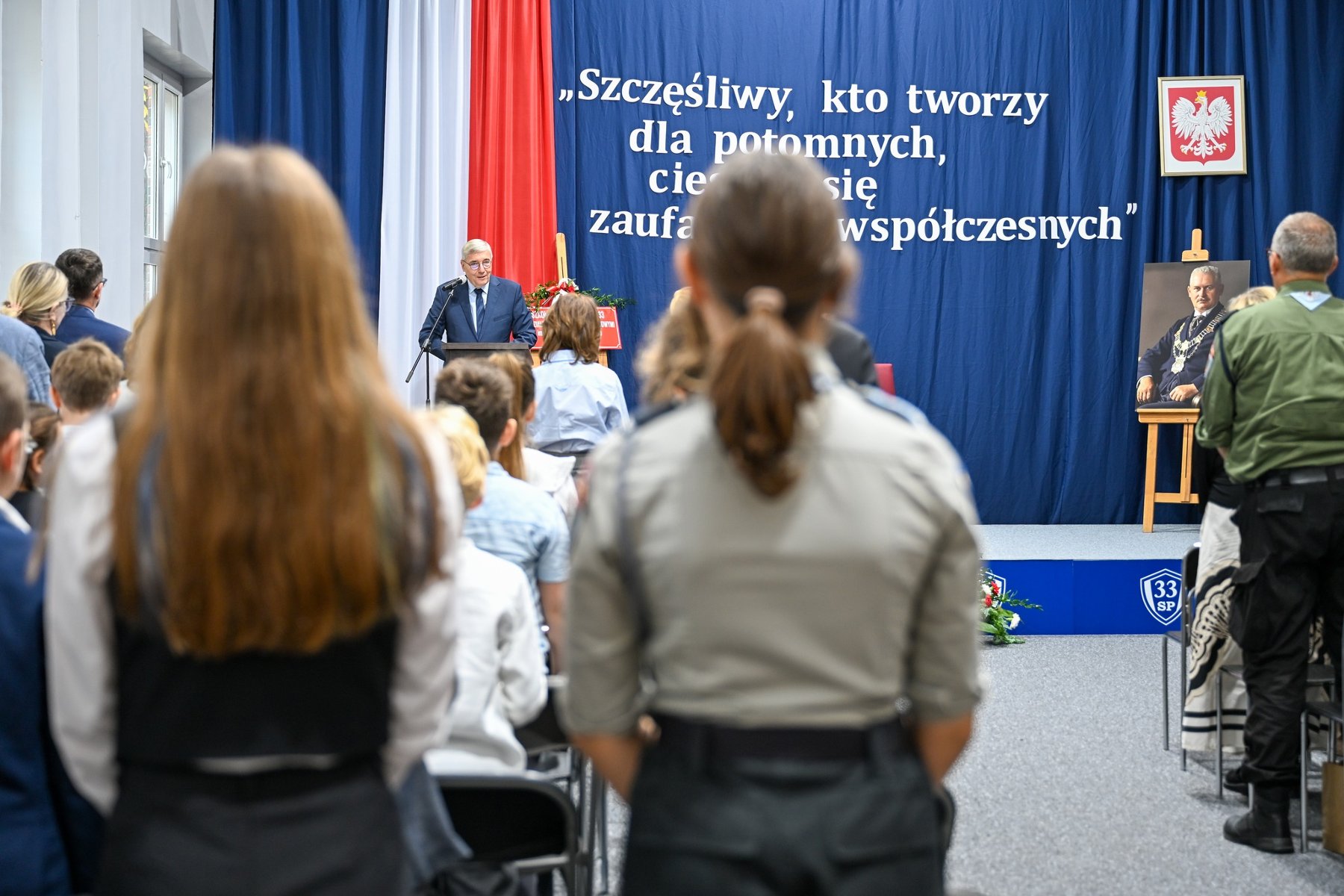 Zdjęcie przedstawia przemawiającego podczas szkolnej akademii przewodniczącego rady miasta.