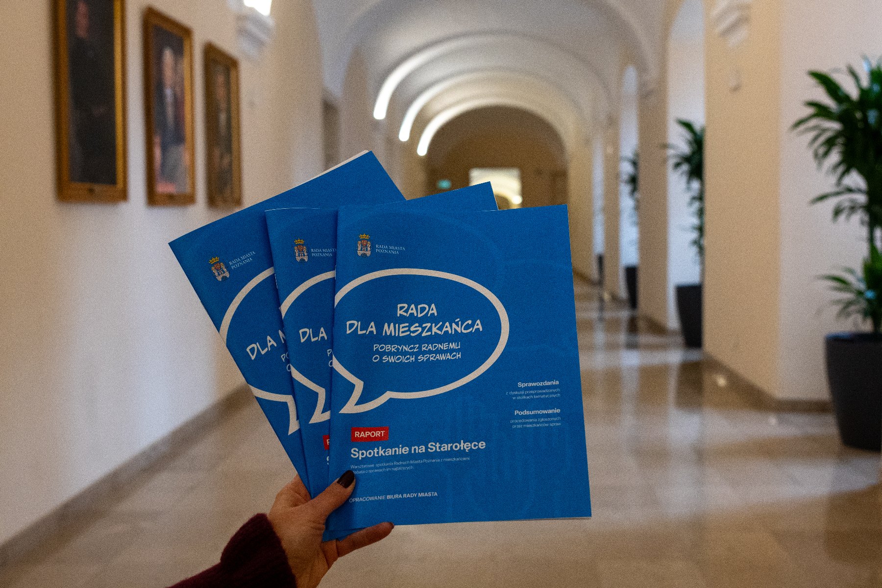 Zdjęcie przedstawia raporty na tle holu.