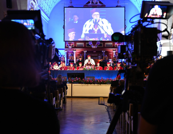 Zdjęcie przedstawia rektora przy mikrofonie i władze uczelni za stołem.