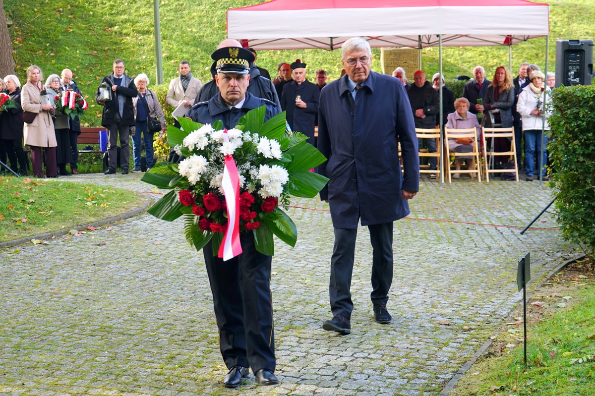 Zdjęcie przedstawia składającego kwiaty przewodniczącego rady miasta.