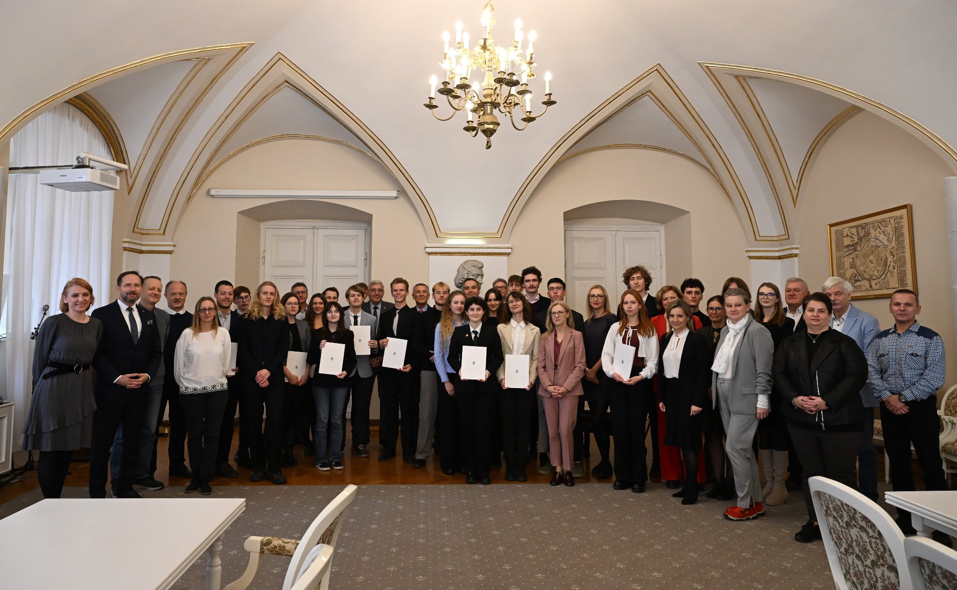 Zdjęcie przedstawia starszego mężczyznę wręczającego dyplom młodszemu.