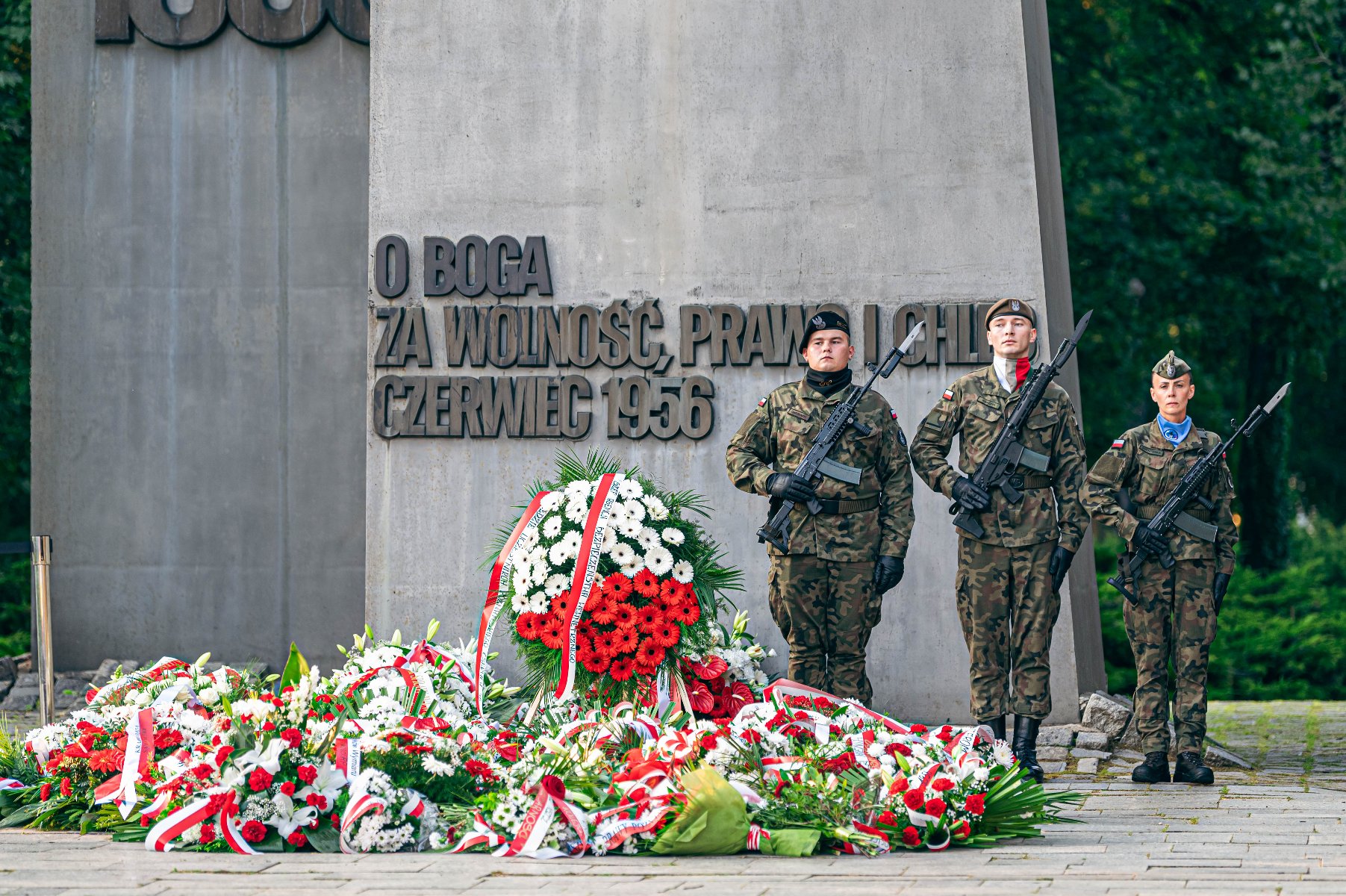 Zdjęcie przedstawia wiązanki kwiatów leżące pod pomnikiem Poznańskiego Czerwca 1956 roku.