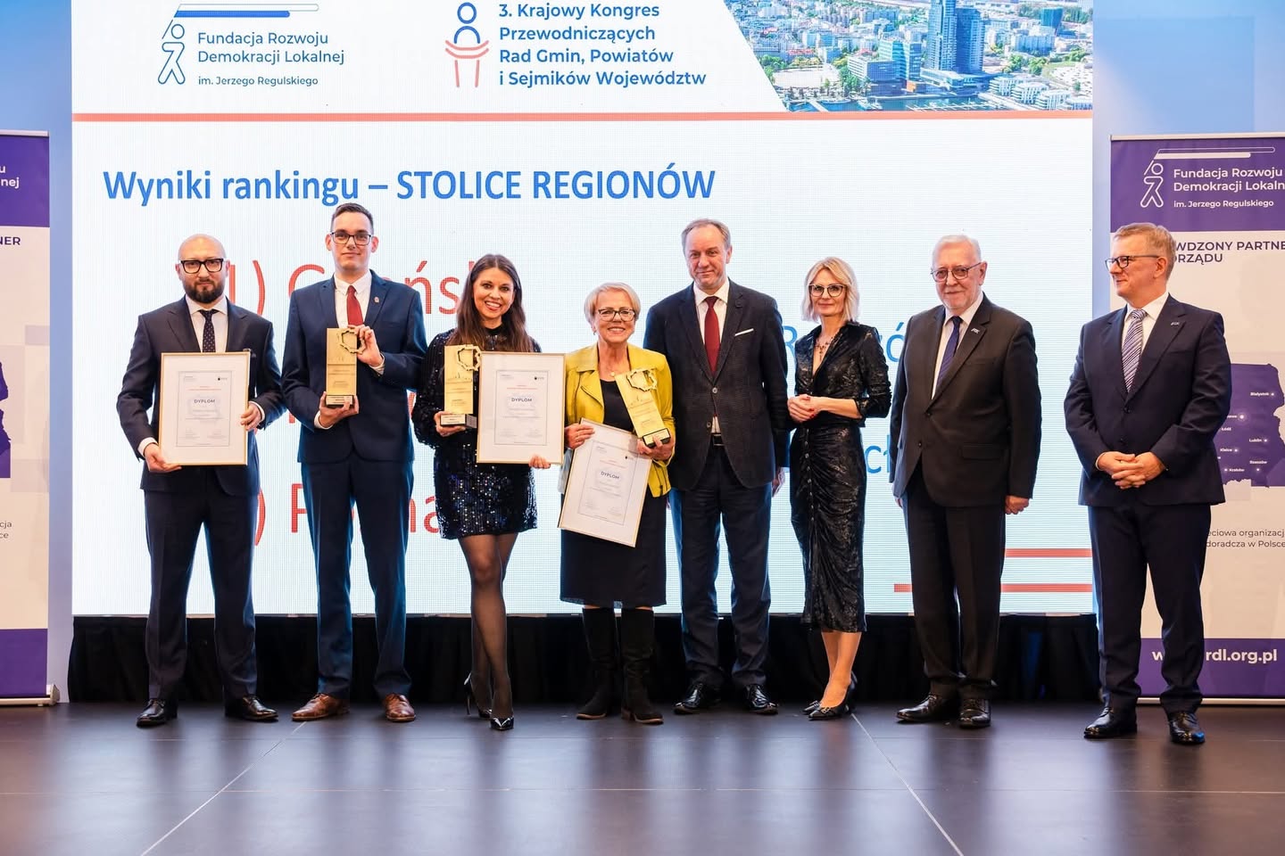 Zdjęcie przedstawia wręczanie wyróżnienia na ręce wiceprzewodniczącego rady miasta.