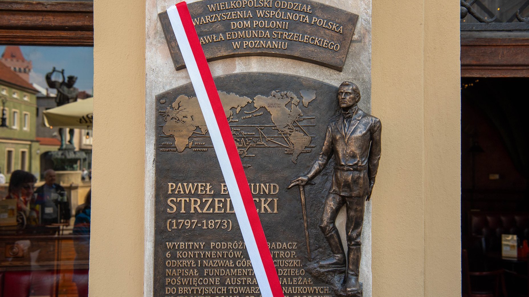 Zdjęcie ukazuje tablicę poświęconą Pawłowi Edmundowi Strzeleckiemu na fasadzie Domu Polonii.