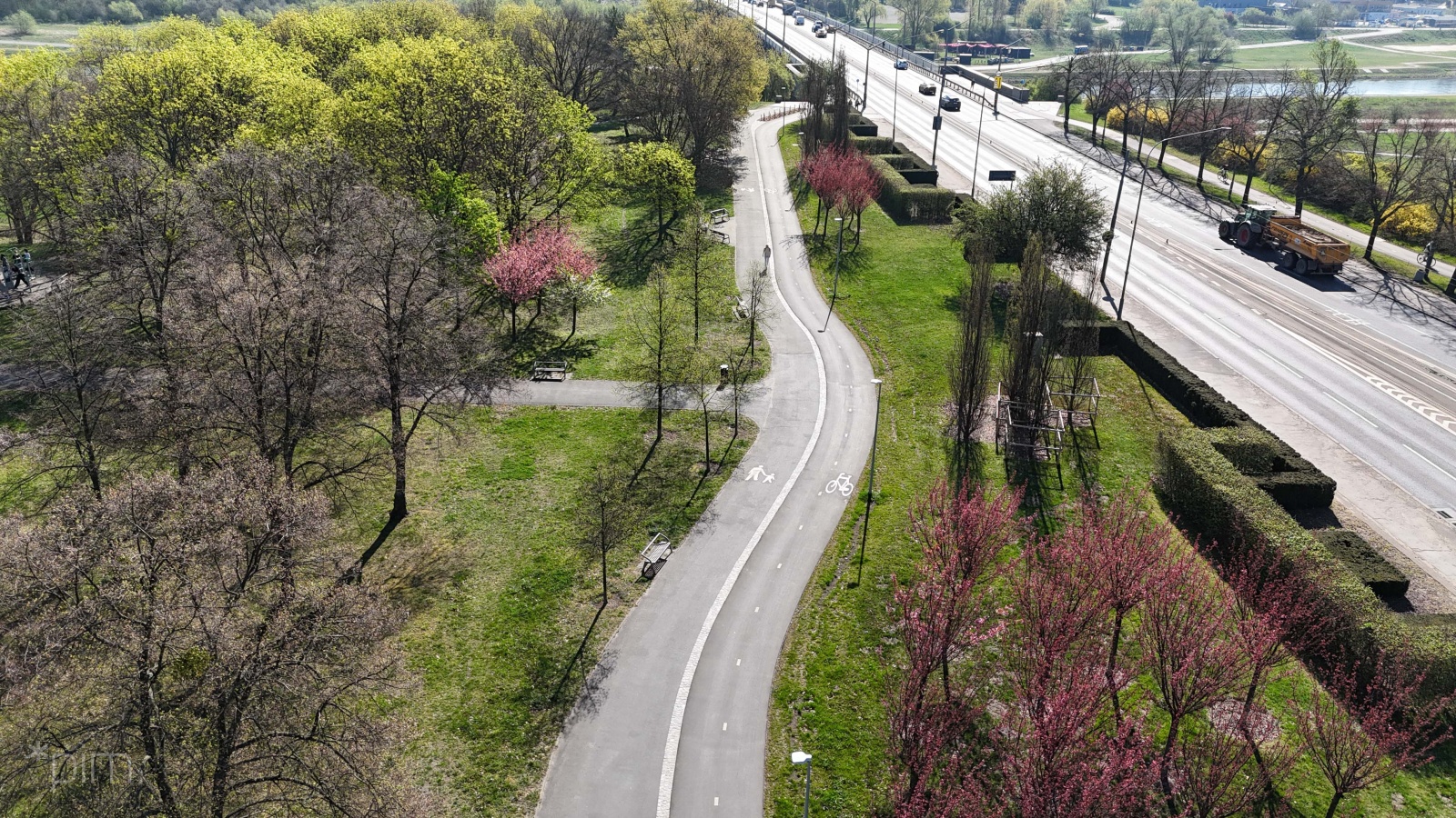 Zdjęcie z lotu ptaka na fragment drogi rowerowej, ulicy samochodowej i parku miejskiego.