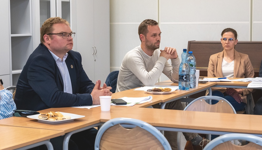 dwóch mężczyzn i kobieta siedzą za stołem w sali konferencyjnej - grafika artykułu