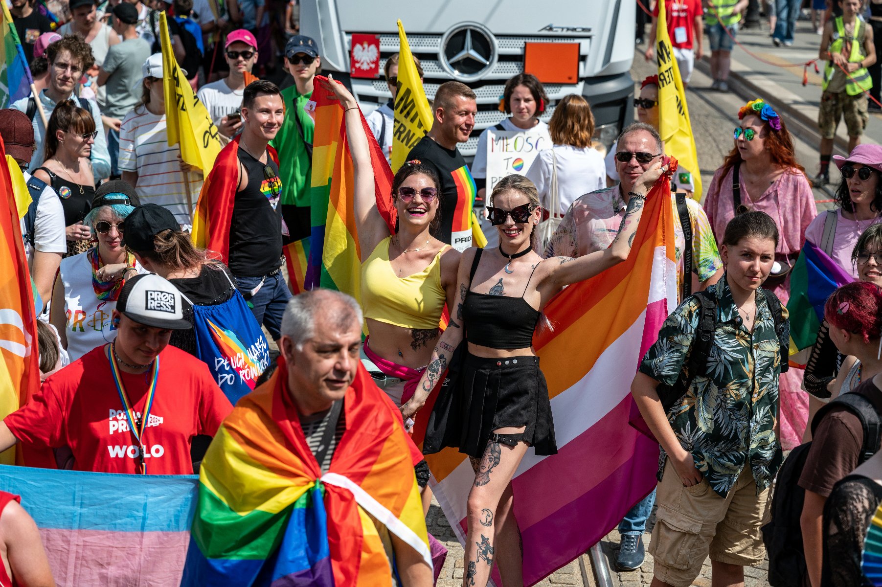 Na zdjęciu uśmiechnięci ludzie ubrani w tęczowe kolory