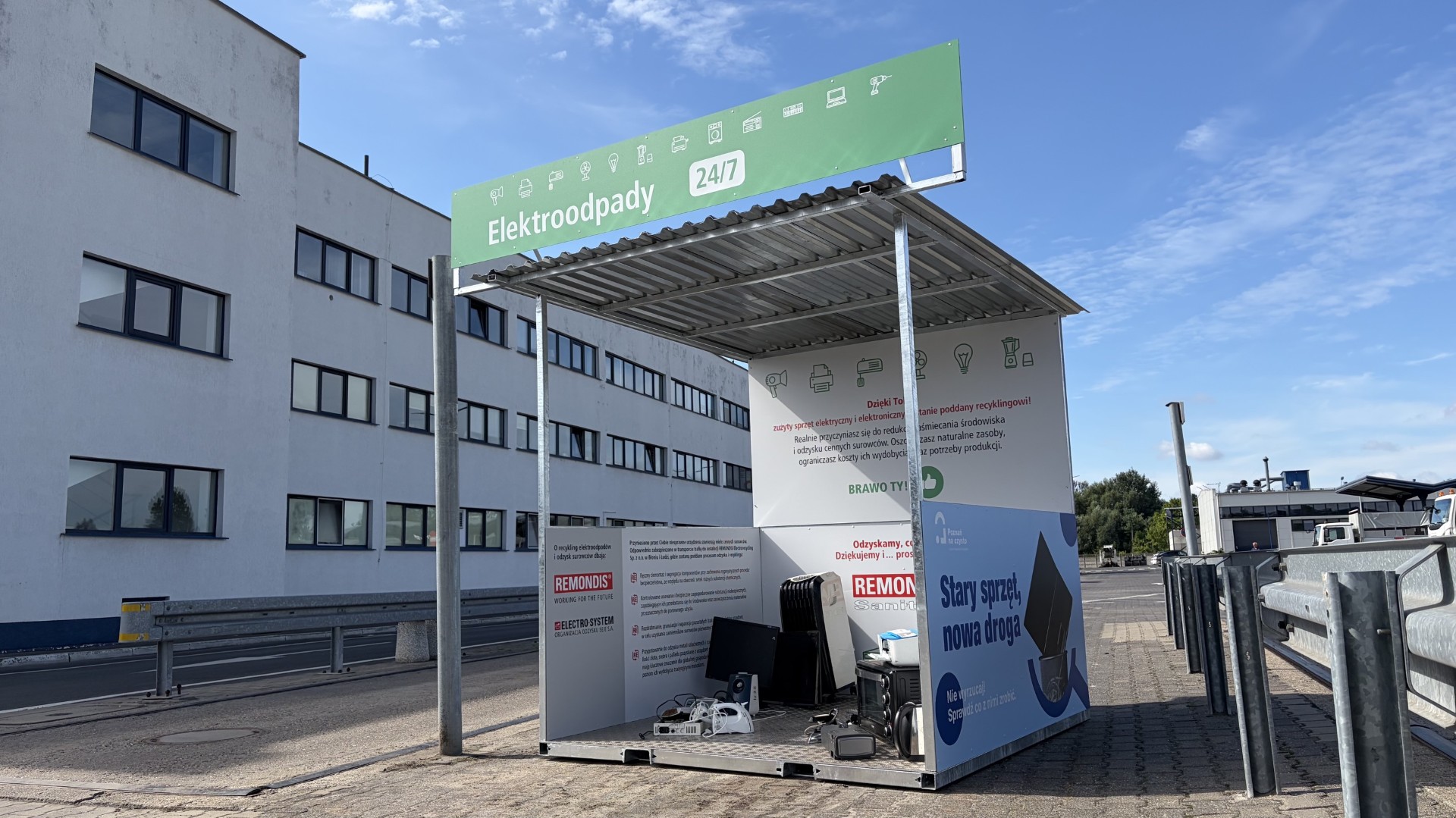 Na zdjęciu widoczny jest kontener do składowania elektroodpadów. Jest oznakowany treściami edukacyjnymi i informacjami dotyczącymi funkcjonowania systemu