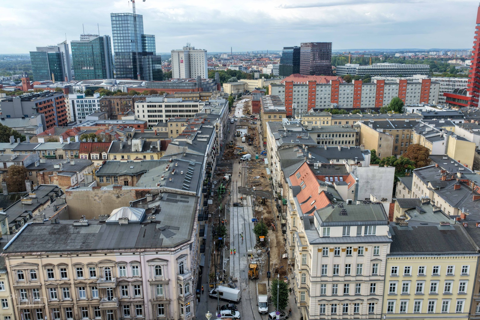 Na zdjęciu widok na miasto z góry. Pomiędzy budynkami rozkopana ulica. Nowe fragmenty torów tramwajowych.