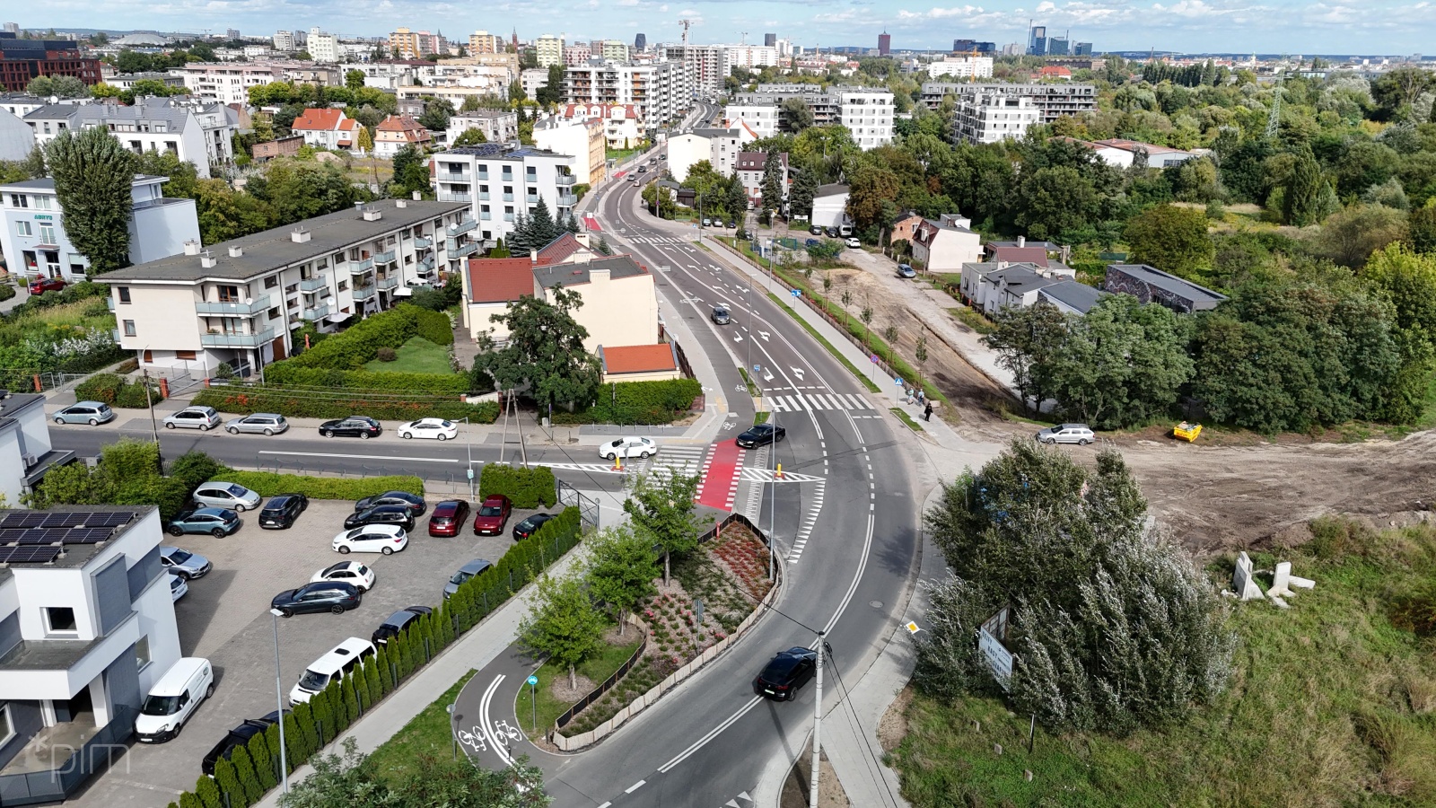 Nowa droga rowerowa wzdłuż ul. Dmowskiego. Wokół widać domy i bloki. W oddali centrum Poznania