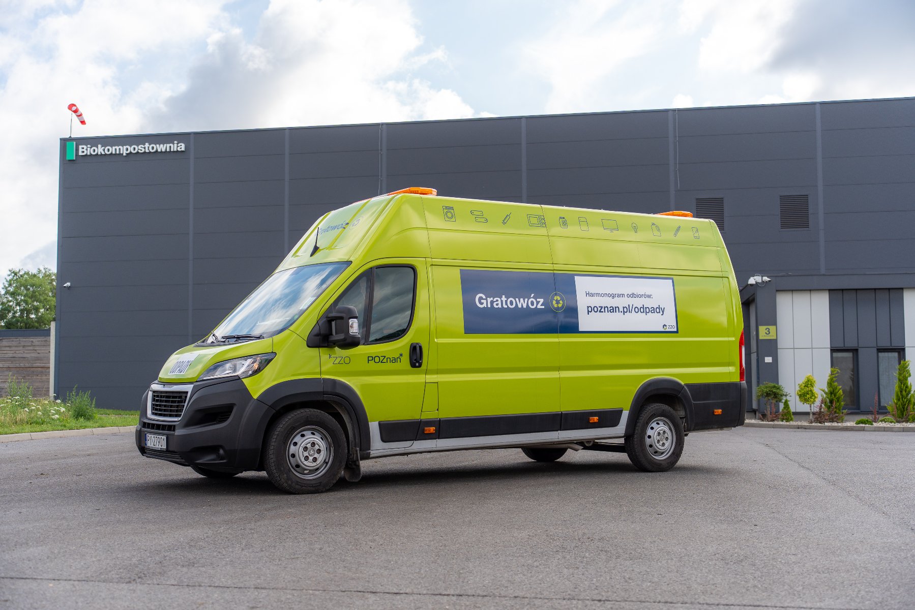 Zdjęcie przedstawia samochód typu bus, odpowiednio oznakowany i przystosowany do przewożenia odpadów