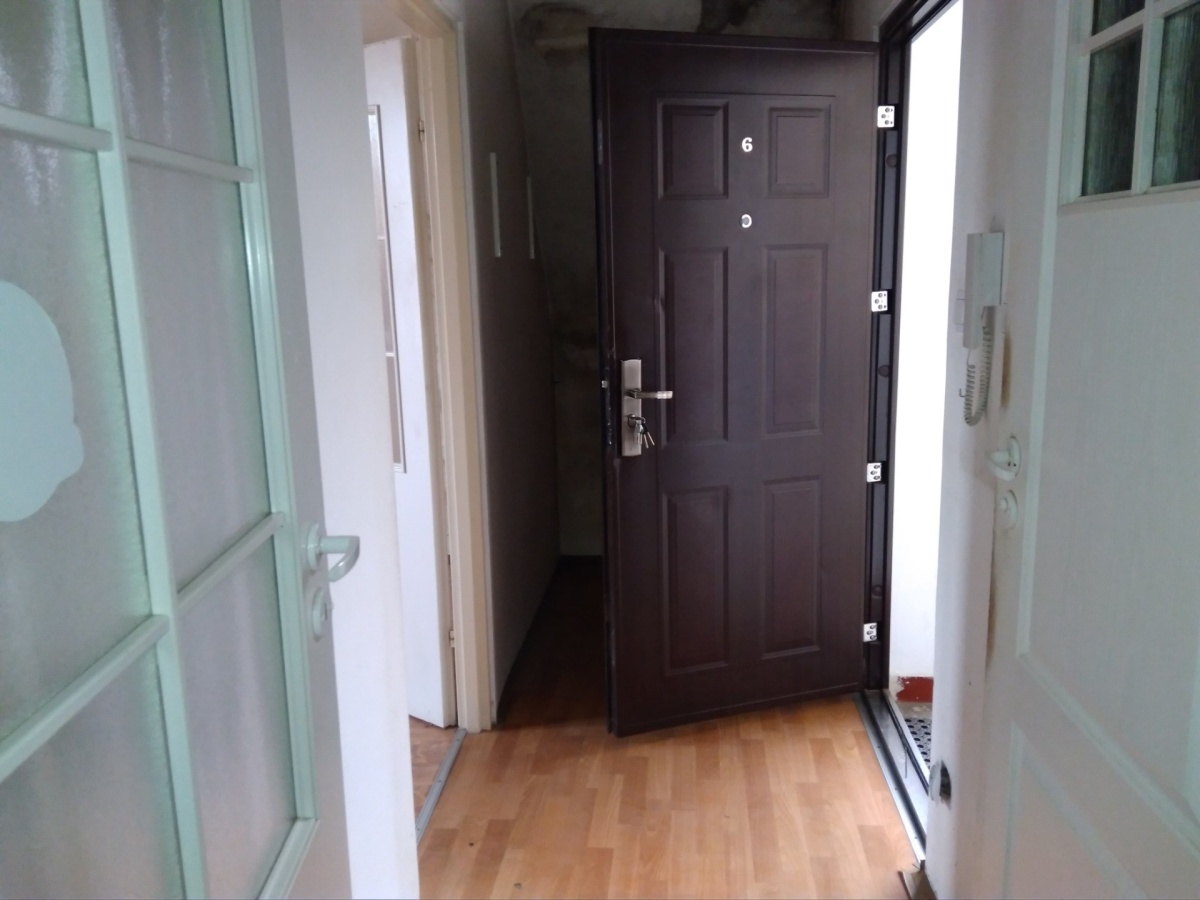 Zdjęcie przedstawia wnętrze mieszkania. Widać na nim korytarz i drzwi.