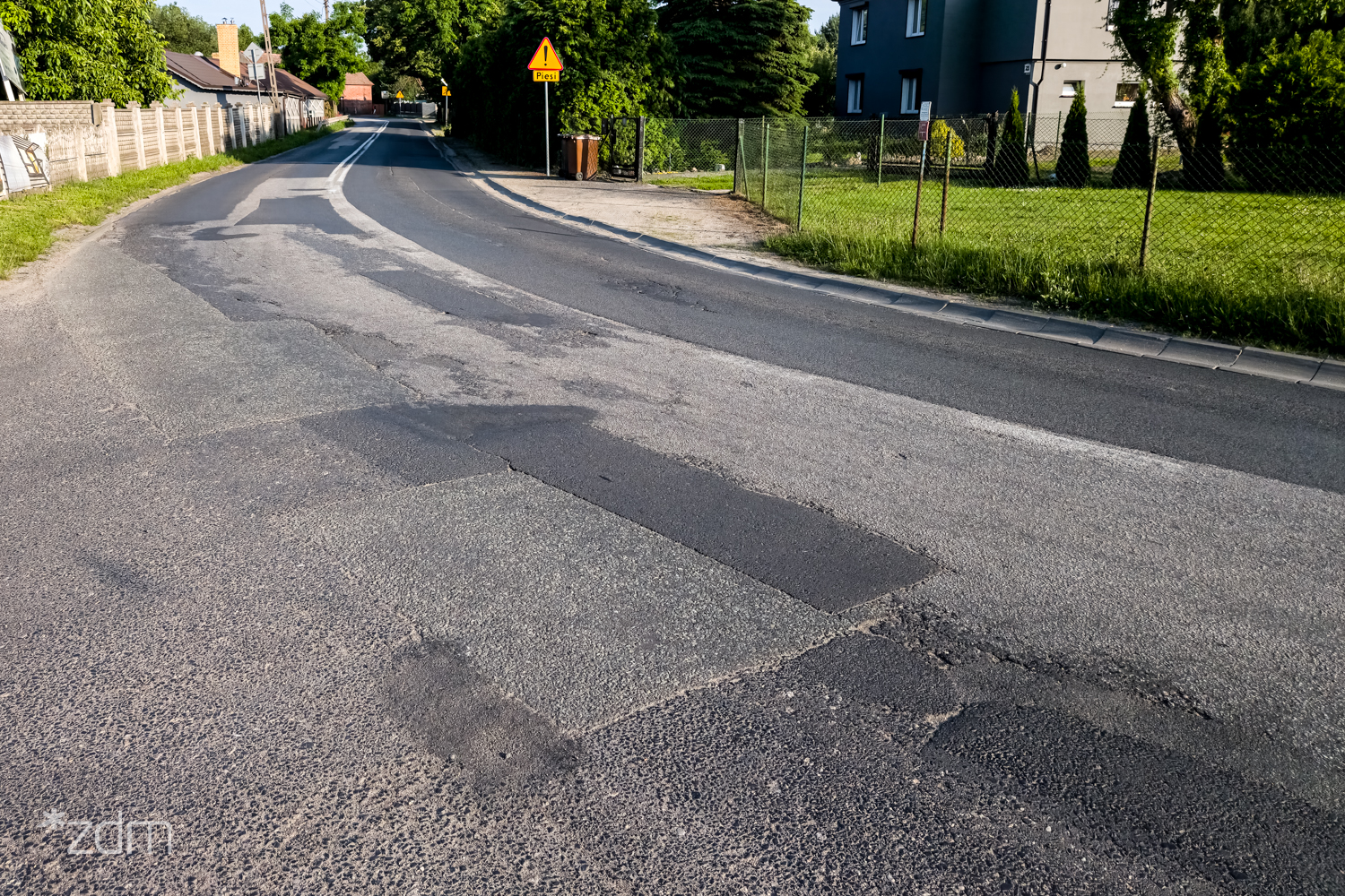 Zniszczona nawierzchnia ul. Radojewo na zakręcie drogi